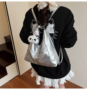 Détail du sac à dos Hobo argenté métallisé avec une peluche panda sur l'épaule