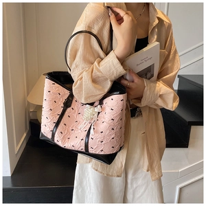 Détail du sac cabas rose avec motifs nœuds noirs et pendentif élégant en perles et dentelle