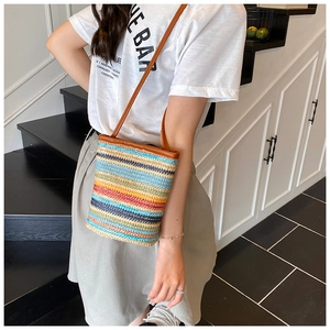 Detail of colorful woven straw texture and leather shoulder strap on a summer bucket bag