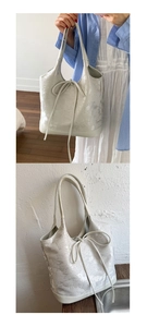 Detail of light grey tote bag featuring butterfly patterns and soft ribbon bow detail