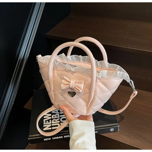 Detailed view of pink quilted handbag with bow charm and white lace trim detail