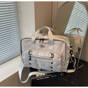 Detail of grey travel bag with durable nylon fabric, elastic straps and front logo