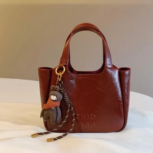 Vintage burgundy leather handbag with bear charm and Chic 200 embossing on white surface