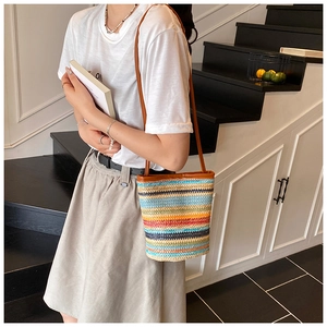 Detail of colorful striped woven bucket bag with brown synthetic leather shoulder strap