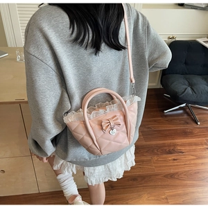 Close-up of pink quilted handbag with delicate lace ruffles and heart bow charm detail