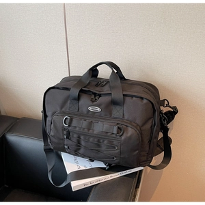 Close-up of black travel bag showing nylon texture, zip pocket, and sturdy handles