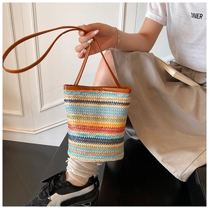 Detail of colorful woven straw bucket bag featuring blue, yellow and navy stripes