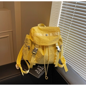 Detail of yellow backpack featuring metal buckle closure and textured nylon fabric