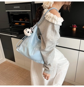 Détail du cabas en cuir verni bleu clair avec une breloque décorative en peluche panda