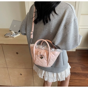 Detail of pink quilted bucket bag with lace trim and bow, shown on model in daily setting