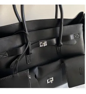Detail of the high-quality black leather tote bag with silver metal buckles and stitching