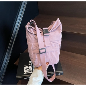 Detalle de bolso tipo cubo de nailon rosa con cierre de hebilla negra en madera