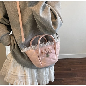 Detailed view of pink quilted bucket bag with bow decoration and heart charm on a model
