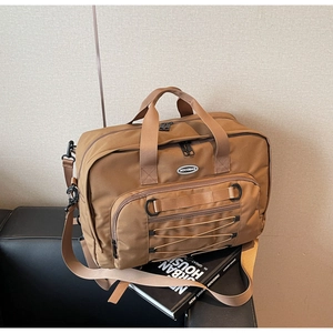 Detail of khaki travel bag with thick handles and crisscross elastic cord on black leather