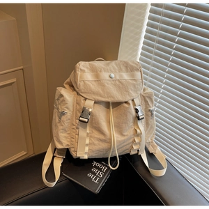 Close-up of cream nylon backpack with flap closure and adjustable metal buckles
