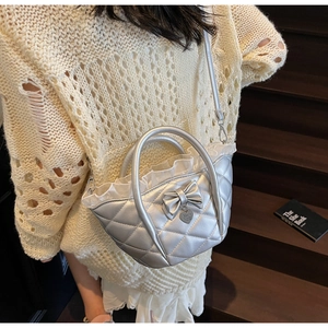 Macro detail of silver quilted bucket bag with lace trim and heart pendant