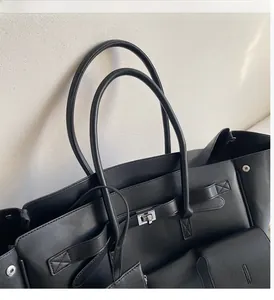 Close-up of black leather tote bag featuring textured finish and silver metal buckle