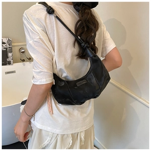 Detail of a black hobo shoulder bag with a unique knotted strap design for a stylish look