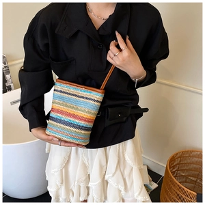 Close-up of colorful striped straw woven crossbody bag with brown leather strap detail