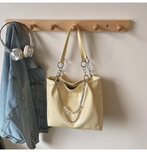 Detailed close-up of cream tote bag with crinkled texture and decorative pearl chain link