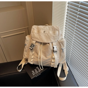 Dettaglio dello zaino in nylon beige con fibbie funzionali e chiusura a coulisse