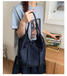 Close-up of black polka dot bucket bag with decorative bow held in a lifestyle setting