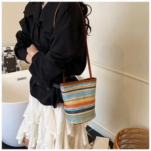Detailed shot of rainbow striped woven bucket bag with brown leather shoulder strap