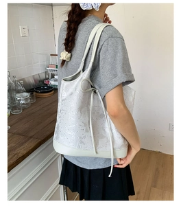 Detail of grey tote bag with embossed butterfly pattern and drawstring closure