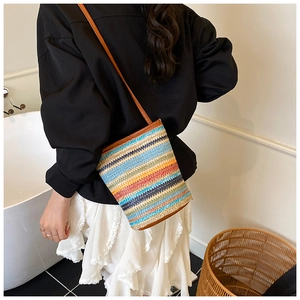Detail of colorful striped woven bucket bag with brown leather strap in a lifestyle setting