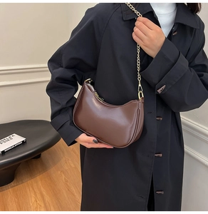 Detail view of a dark brown crescent moon bag featuring a gold chain and smooth leather finish