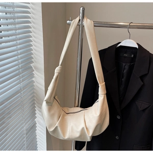 Detail of cream pleated leather dumpling bag with knotted strap and zipper closure