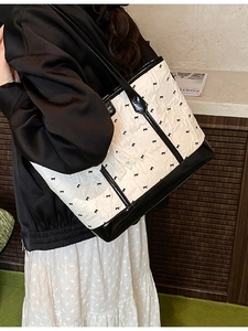 Minimalist beige quilted tote bag with black bow print and glossy leather straps