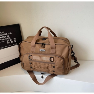 Detail of a large brown canvas travel bag featuring a side zipper pocket and bungee cords