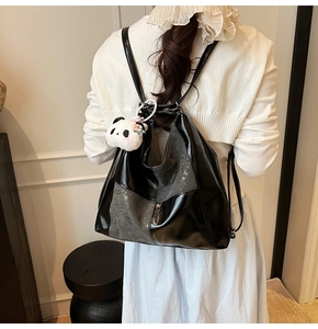 Détail d'un sac à dos en similicuir noir brillant avec pendentif panda pour le quotidien