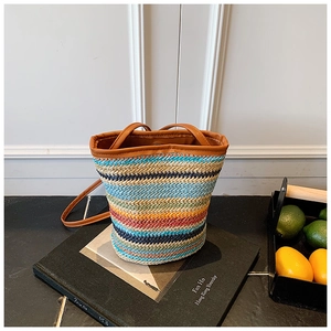 Detail of colorful striped straw bucket bag with brown leather strap and woven texture