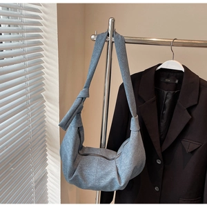 Detail of grey-blue dumpling bag featuring knotted wide strap and smooth zipper closure