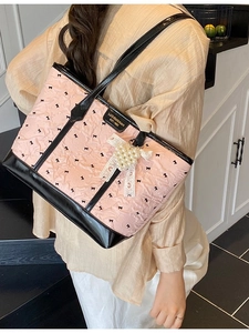 Pink tote bag with black bow prints and lace pearl heart charm in a modern interior