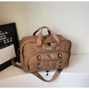 Macro shot of brown travel bag featuring front zipper pocket and adjustable shoulder strap