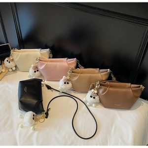 Detail of five stylish leather dumpling bags with cute plush charms and gold logos