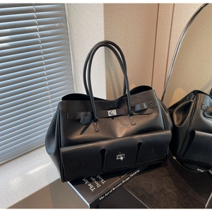 Close-up of black leather tote bag featuring utility pockets and metallic twist lock detail