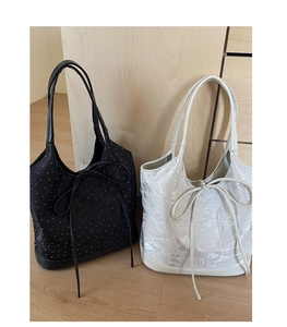 Detail of jacquard texture and bow decoration on black and cream tote bags