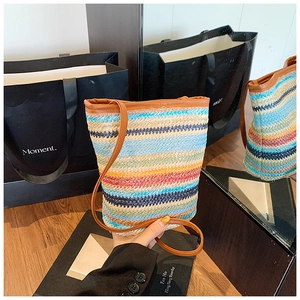 Detail showing rainbow woven straw texture and premium brown leather shoulder strap