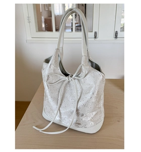 Close-up of cream white tote bag featuring intricate floral embroidery and bow detail
