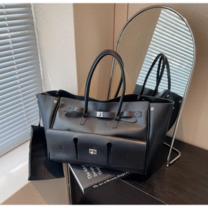 Close-up of black leather tote bag featuring a silver twist lock and minimalist texture