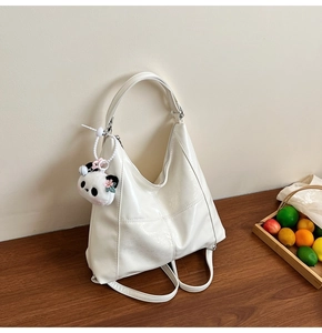 Détail d'un sac cabas en cuir verni blanc avec un porte-clés panda en peluche mignon