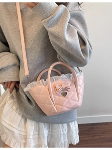 Pink quilted bow bucket bag with heart pendant shown as a stylish crossbody bag