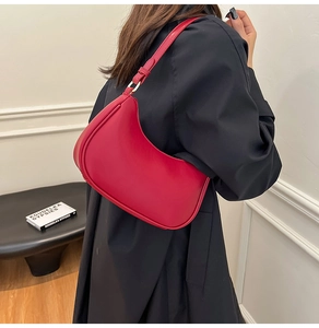 Detail of red crescent hobo bag with fine stitching and gold metal buckle on shoulder strap