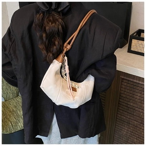 Chic cream dumpling bag with tassel charm styled on a black oversized blazer