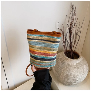 Close-up of colorful straw bucket bag with blue yellow and red stripes and leather trim