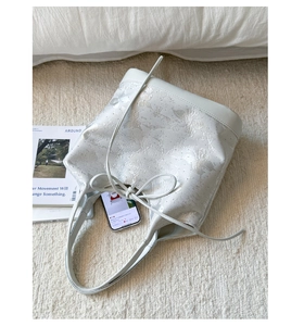 Detail of elegant bucket bag featuring pearl-texture butterfly jacquard and bow drawstring
